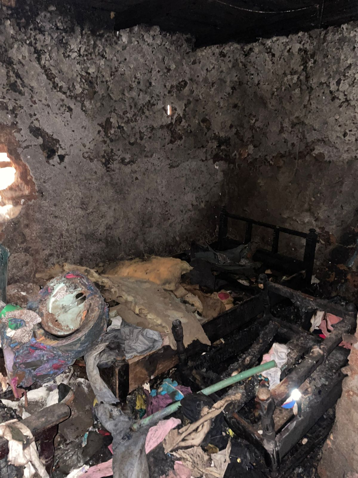 6de1c3eb-9757-4ddd-a992-2a18f1b3bbc6 A Kibera home devastated by fire showing the interior with burnt and ruined possessions and damaged structure.