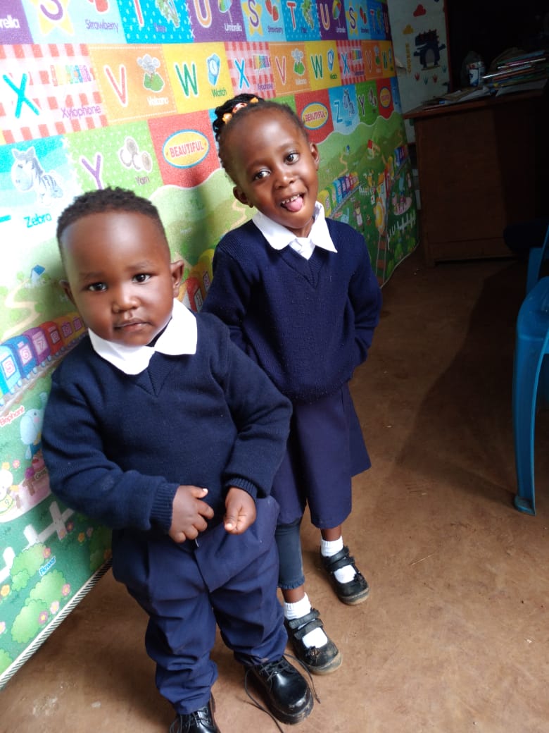 5418f7f1-bbf4-447d-b410-38ff58ed7b20 Two small children, a boy and a girl, pose for the camera. They are wearing the navy blue and white uniform of the Bornstar Children's Centre.